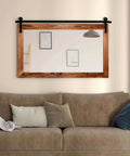 Farmhouse Barn Door Mirror With Rustic Wood Frame 41 By 26 Inches mounted over living room sofa for decor in brown finish