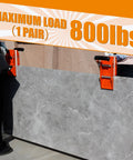 Granite carrying clamps (2-pack), orange with rubber-lined jaws gripping a large gray stone slab