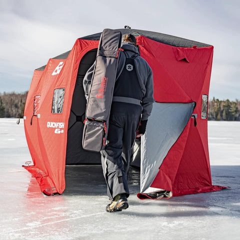 Person entering Quickfish Six Person Portable Pop Up Ice Fishing Shelter With Fully Quilted Insulation No Trip Door And Deluxe Anchors For Hell Of A Winter Setup In Red Black.