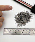 Tough As Nails Premium 304 Stainless Steel Screw Eye Hooks 5Mm By 10Mm displayed on a finger with measuring ruler for size reference.