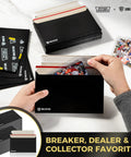 7 By 4.35 Inch Black Card Mailers For Trading Cards Self Adhesive Premium Shipping Envelopes That Fit Semi Rigid Sleeves Toploaders And Ding Defend Protectors Perfect For Hobby Card Shipping shown with hands inserting trading cards.
