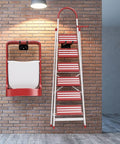 Foldable ladder with red and white steps mounted on brick wall, showcasing storage solution