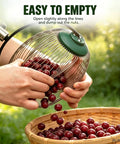Hands using Straight Up Easy Roll Pine Cone Picker Upper With Telescoping Handle and Wide Steel Basket to empty nuts into a basket.