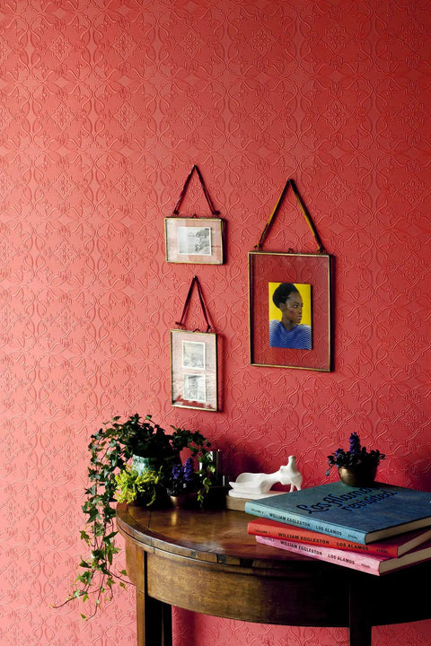 Interior wall with red textured wallpaper, plants, and paintings. Maxwell White Paintable Textured Vinyl Wallpaper Unpasted Washable Strippable 21 In By 33 Ft Double Roll With Straight Match And Six Point Twenty Five Inch Repeat Ideal For DIY Home Makeovers.