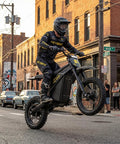 Dual Pack Off Road Beast Mode Electric Dirt Bike With 4160W Mid Drive Motor And 52V 26Ah Battery rocking fat tires on a city street.