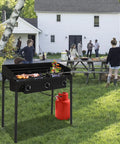Three-Burner Outdoor Propane Stove With Detachable Stand And Windscreen in use at a backyard party