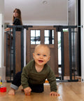 Farmhouse Style Barn Door Walk Thru Baby Gate With Dual Swing Stylish Auto Close 30 Inch Tall Fits 29 To 43 Inch Openings Wood And Black Finish Whisper Quiet Hinges Safe Stair Stop For Modern Homes, showing a baby crawling on the floor with gate in background