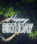 Person holding massive Happy Birthday neon sign for wall decor with dimmer switch, 12V reusable light, 27.5 x 17 inches, lit up.