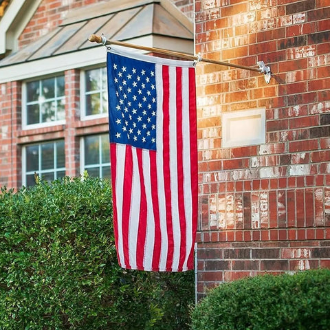 Heavy Duty 5x8 Ft US Flag With Embroidered Stars And Sewn Stripes hung on house wall, nylon construction, brass grommets visible