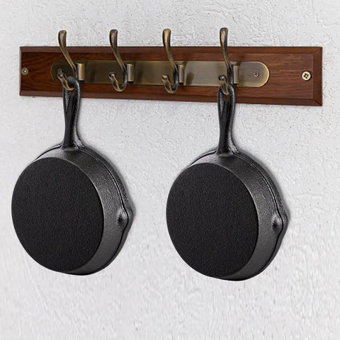 Two mini cast iron skillets hanging on a wall hook, part of the Four Pack Mini Cast Iron Skillets 4 Inch With Double Drip Spouts