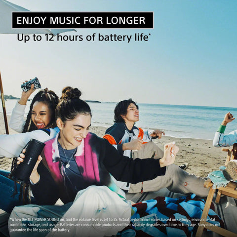 Group of friends at the beach enjoying music with the Ultimate Field 1 Waterproof Portable Bluetooth Speaker. Woman holding speaker.