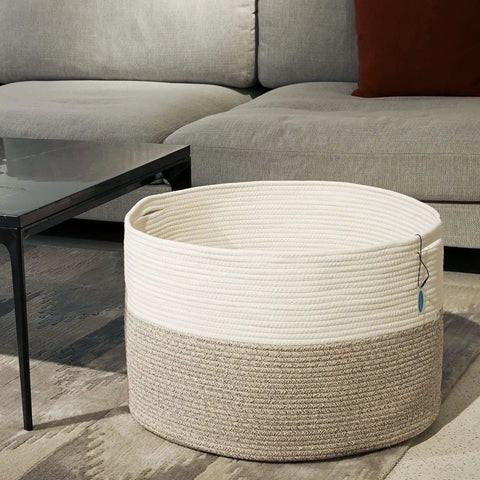XXXL Cotton Rope Storage Basket With Handles For Blankets Towels And Pillows, Jumbo Woven Laundry Hamper, White And Brown, 22 By 22 By 14 Inches placed in a modern living room setting.