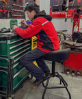 Person using Garage Shop Stool With Backrest Height Adjustable Pneumatic Bar Stool 25 To 31 Inches Swivel Counter Height Seating For Bar Work Bench Or Kitchen Heavy Duty Steel Frame 330 Pound Capacity Black at a workstation