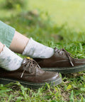 Upgrade Your Daily Drip With Top Tier Metal Alloy Shoe Lace Tips Built To Outlast Worn Aglets on brown shoes in grass.