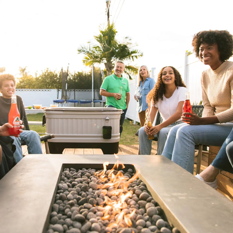 People enjoying drinks near a 125 Qt Gray Party Bar Wheeled Cooler With Ultratherm Insulation Removable Lid That Converts To Open Air Beverage Tub.