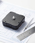 WhisperSilent Quartz Wall Clock Movement Kit With 8mm No Thread Shaft For DIY Projects And Home Decor Ensures Exact Time Output Plus Silent Sweep Second Hand For Bedroom Or Office Use on blueprint with measuring tools.