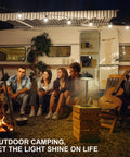 Outdoor camping scene with a Cordless Table Lamp With 5200mAh Battery, on a table beside a camper, illuminating a group of people.
