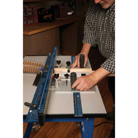 Person using Router Table Coping Sled Kit With Sacrificial Backing Board And Adjustable Fence Guide Spacers Includes Toggle Clamp Handles And Hardware Pack For Safe Quick Setup And Precise Coping Cuts In Wood Up To One And One Eighth Inches Thick For Pros on a blue router table