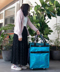 Person using Glitter Blue Rolling Grocery Tote With Wheels and Zipper Covered 8 Pocket Organizer, medium size, outdoor setting
