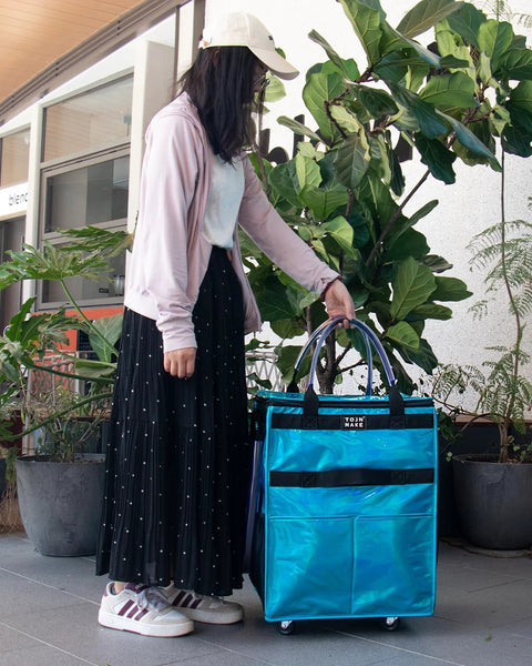 Person using Glitter Blue Rolling Grocery Tote With Wheels and Zipper Covered 8 Pocket Organizer, medium size, outdoor setting