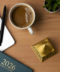 Three Layer Rotating Pyramid Fidget Toy For Stress Relief Desk Meditation Accessory on wood desk with coffee and planner.