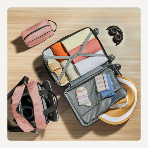 Amazon Basics luggage set in rose gold: 22-inch expandable hardside suitcase open with clothes, plus 15-inch tote and 10-inch travel bag