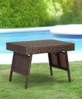 Portable Folding Wicker Table With Steel Frame For Outdoor Use next to pool on grass