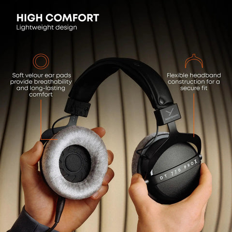 Hands holding DT 770 Pro X Wired Studio Headphones 48 Ohm Closed Back, highlighting soft ear pads and flexible headband.