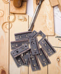 Top-down view of 10-pack stainless steel cabinet hinges on a wooden work surface.