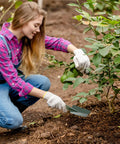 Gardener using 12 Piece Garden Shovel And Trowel Set With Metal Blades And Plastic Handles to dig near a plant.