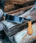 Heavy Duty Eight Inch Curved Draw Shave Tool resting on logs, showcasing durable carbon steel edge and wooden handle.
