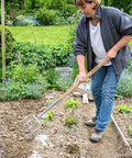 Person using Heavy Duty Garden Pitchfork And Spade Set With 4 Tine Stainless Steel Fork And 47 Inch Long Handle in a garden