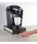 Rolling Mini Black Finish K Cup Drawer Organizer For Under Coffee Pot Storage holding a coffee machine on a countertop