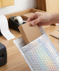 Packing a box into Glitter Bubble Mailers 30 Pack Tear Resistant Shipping Bags For Jewelry Makeup Gifts And Small Items Thick Protective.