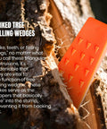 Side view of orange plastic tree felling wedge with spikes embedded in a log.