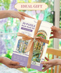Hands holding a wrapped DIY Book Nook Kit For Grownups 3D Wooden Miniature House Puzzle With LED Lights Dust Cover And Bookend Insert