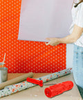 Heavy Duty Textured Rubber Paint Roller For Decorative Accent Walls DIY Hella Smooth Embossing Designs With Comfortable Grip Handle showing red roller next to wallpaper.