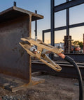 Heavy Duty Brass Welding Ground Clamp For Stick Mig Tigs And Cutting Tasks With Secure Locking Set Screws For Solid Earth Wire Connection In Professional Shop Settings attached to steel beam.