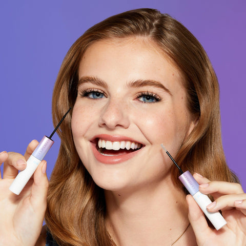 Smiling woman holding All Day Lash Bond And Seal With Biotin And Vitamin E For Falscara Lashes, showing applicator wands.