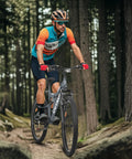 Cyclist on Dope 26-Inch Mountain Hybrid Bike With Steel Frame, 7-Speed Gearing, in forest trail, grey bike.
