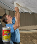 Man applying Original Thick Rubberized Waterproof Tape That Seals Leaks And Patches Underwater Works Indoors Or Outdoors White 8 In By 25 Ft Heavy Duty Tape For Roofs Pools RVs And More UV Resistant And Temperature Tough on a roof tarp.