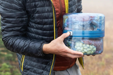Person holding Adjustable Bear Canister For Backpacking And Camping, Expands And Collapses For Bear Resistant Food Storage, One To Four Plus Day Capacity