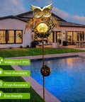 Bronze owl solar garden stake illuminated by pool, showcasing Solar Owl Garden Stake Lights For Lawn And Pathway, IP65 weatherproof.