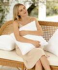 Woman holding 12x20 Outdoor Pillow Inserts Pack Of 2 Waterproof Square Throw Pillows on wicker couch