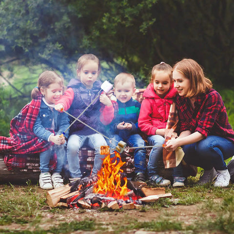 Children and an adult roasting marshmallows using 32 Inch Telescoping Marshmallow Roasting Sticks Set For Campfire Open Fire Pit S'mores Skewers Perfect For Roasting Marshmallows, Hot Dogs, And Sausages, 5 Pack With Bright Color Tips For Easy Grilling And Campout Vibes All Night.