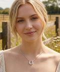 Woman wearing Lucky Horseshoe Necklace for Women with U Shape Pendant in silver tone stainless steel against outdoor backdrop