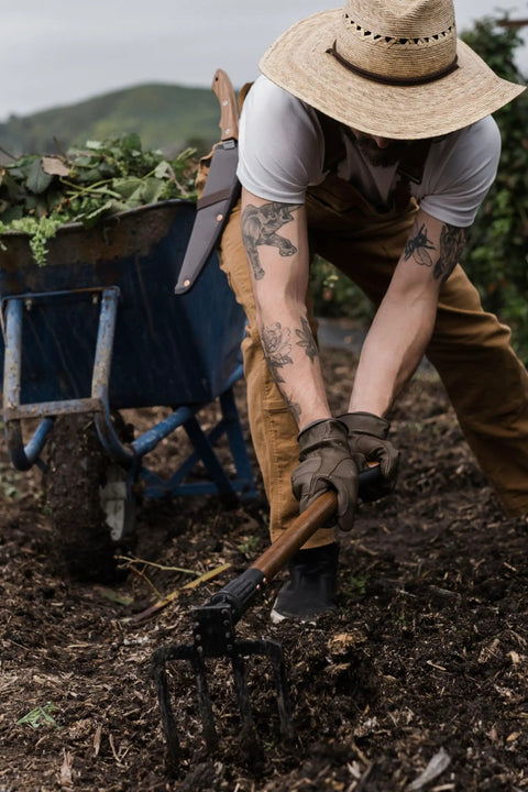 Gardener using Foldable Spading Fork for digging and aerating durable steel garden tool with easy twist lock.