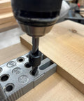 Close-up of a drill using Pro Doweling Kit With Pre-Aligned Hole Guides And Hardened Steel Bushings for uniform joints in wood.