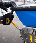 Person adjusting the cover of Spyker Winter Weather Deicing Kit With Ergo Pro 50 Pound Spreader, showing handle and gloves in winter scene.