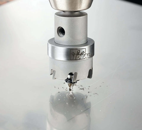 IDEAL carbide hole cutter head cutting metal, front view; silver-colored with IDEAL logo